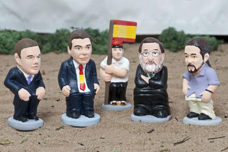 Figuren der vier Parteiführer Albert Rivera (Ciudadanos), Pedro Sanchez (Sozialdemokraten), Mariano Rajoy (Konservative) und Pablo Iglesias (Podemos). Hinten ein katalanischer Bauer mit spanischer Flagge