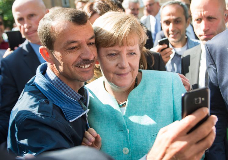 Gruppenbild mit Dame: Angela Merkel lässt sich zusammen mit einem Flüchtling fotografieren