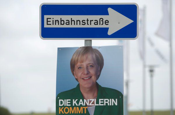 Plakat von Kanzlerin Angela Merkel unter einem Einbahnstraßen-Schild