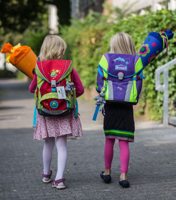 Zwei Mädchen gehen mit Schultüten zu ihrem ersten Schultag in die Schule.