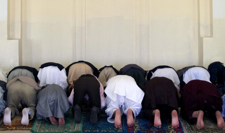 Muslime knien in einer Moschee zum Gebet auf den Boden