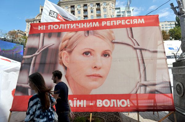 Passanten gehen zur Fußball-EM 2012 in einem Protestcamp in Kiew (Ukraine) an einem Plakat mit einem Portrait der ukrainischen Oppositionspolitikerin Julia Timoschenko und der Aufschrift "Nein zu politischen Repressionen" vorbei