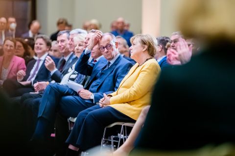 Friedrich Merz und Angela Merkel sitzen im Publikum