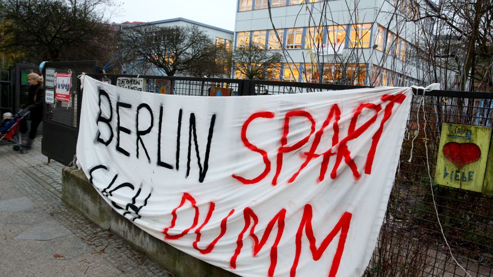 Ein Transparent mit der Aufschrift "Berlin spart sich dumm" hängt vor einem Schulgebäude in Berlin-Steglitz
