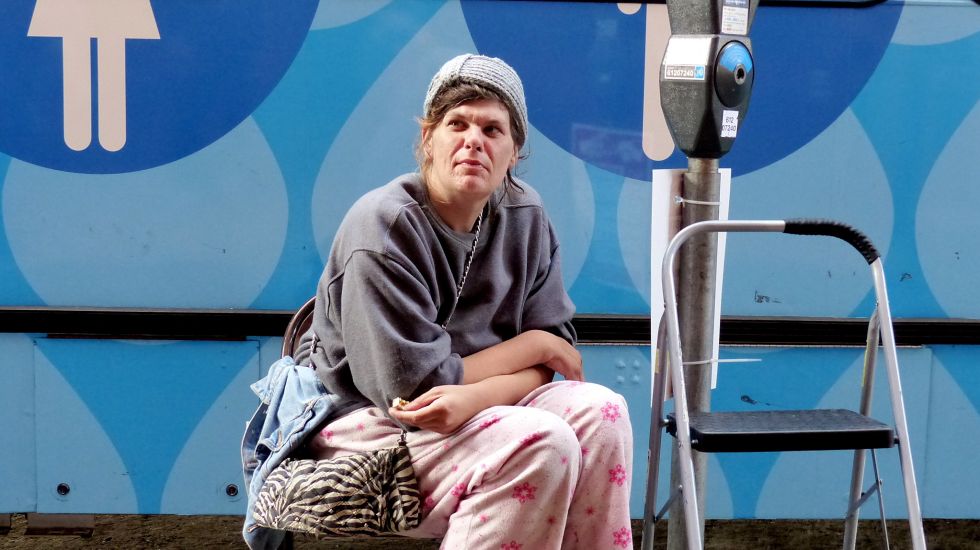 Eine obdachlose Frau wartet von einem Bus mit öffentlichen Duschen