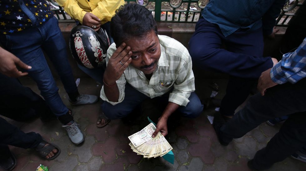 Ein indischer Mann hält ein Bündel Geldscheine in der Hand, während er in der Schlange vor der Indischen Bundesreservebank wartet w