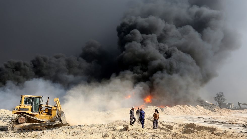 Irakische Ölarbeiter versuchen ein Feuer in einer Ölraffinereie einzudämmen, nachdem sie vom IS befreit wurde