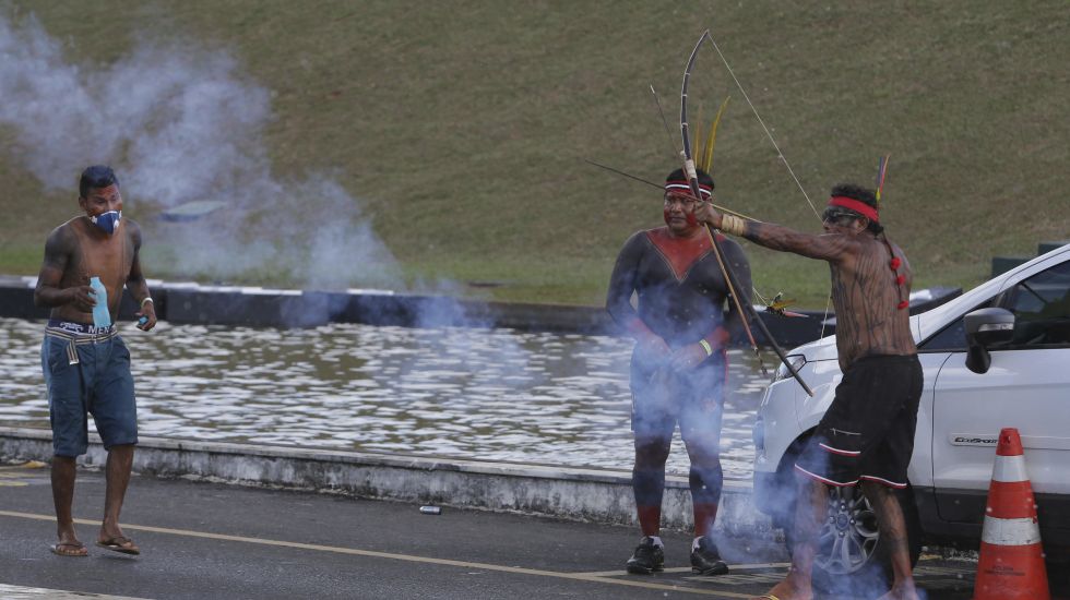 Inmitten von Tränengas, das von der Polizei eingesetzt wurde, spannt ein Indigener seinen Pfeil und Bogen