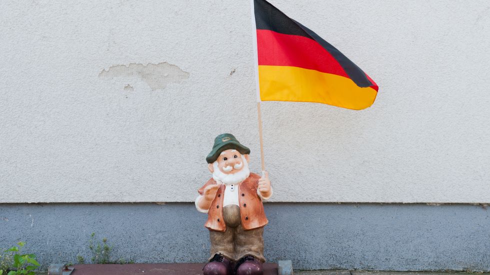 Ein Gartenzwerg steht am 11.07.2014 in Hannover (Niedersachsen) mit einer Deutschland-Flagge an einer Hauswand.