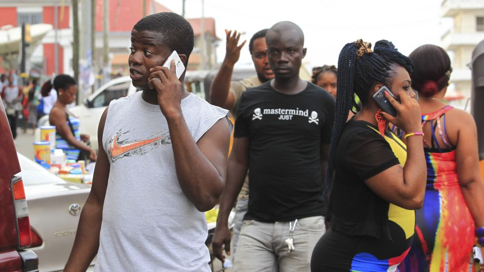 Menschen in Monrovia. Liberia, gehen durch die Straßen mit Mobiltelefonen am Ohr  