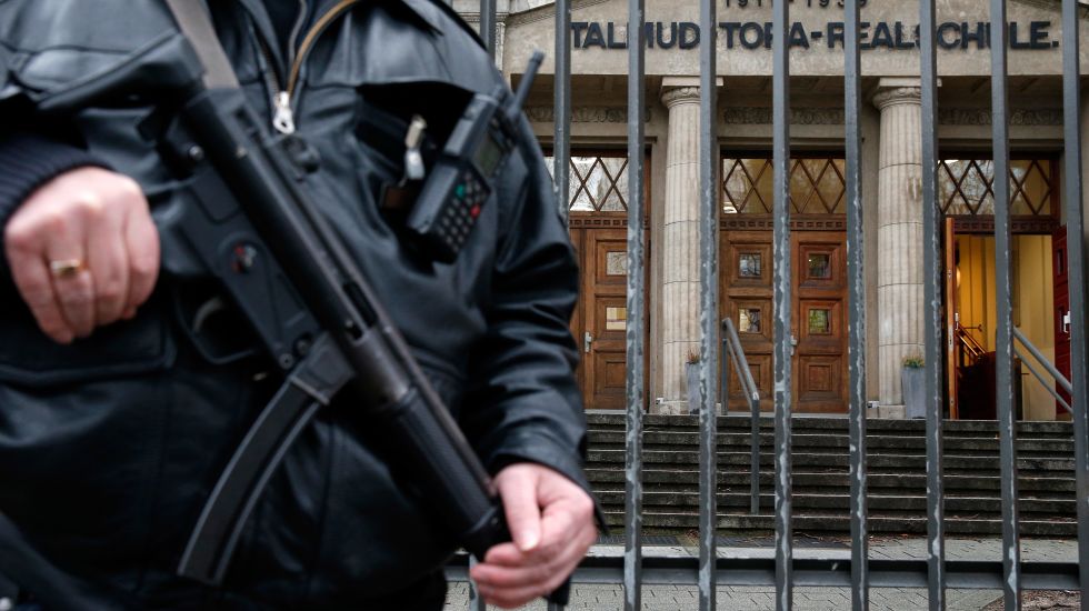Ein Polizist steht mit einem Maschinengewehr vor dem Gebäude der jüdischen Talmud-Tora-Schule in Hamburg