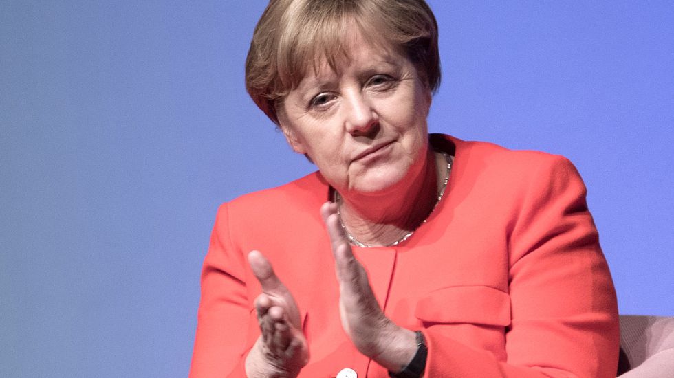 Angela Merkel applaudiert auf einem Podium