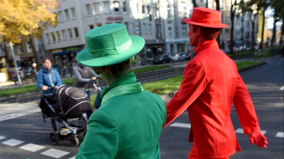 Zwei als Ampelmännchen verkleidete Pantomimen sollen am 27.10.2015 an einer Kreuzung in Köln (Nordrhein-Westfalen) Fußgänger animieren auf die Signale der Ampel zu achten