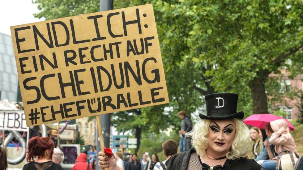 Eine transsexuelle Frau hält ein Schild mit der Aufschrift "Endlich: Ein Recht auf Scheidung #Ehefüralle".