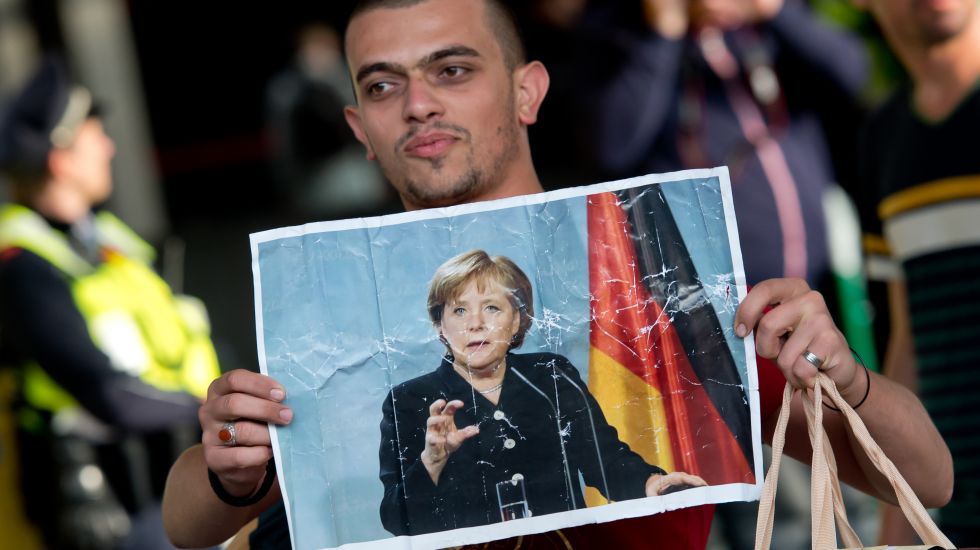 Ein Flüchtling, der kurz zuvor mit einem Zug angekommen ist, läuft am 05.09.2015 auf dem Hauptbahnhof in München (Bayern) über den Bahnsteig und hält dabei ein Foto von Angela Merkel in den Händen. 