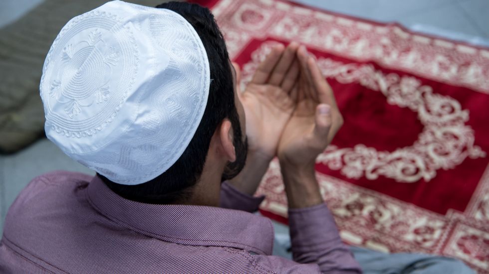 Ein Muslim kniet auf seinen Gebetsteppich und betet