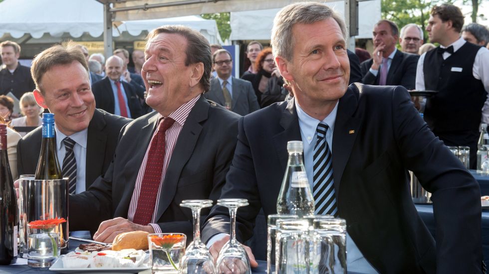 Alt-Bundeskanzler Gerhard Schröder (SPD, M) sitzt am 30.06.2014 zu Beginn der Sommerfestes in der Landesvertretung von Niedersachsen in Berlin neben Alt-Bundespräsident Christian Wulff (CDU). Links sitzt der Vorsitzende der SPD-Bundestagsfraktion, Thomas Oppermann.