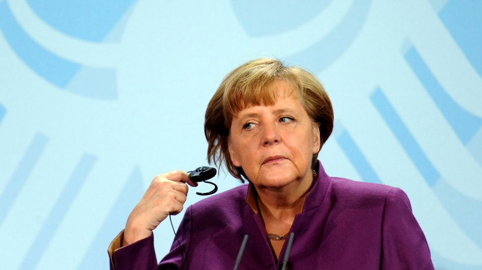 Bundeskanzlerin Angela Merkel nimmt bei einer Pressekonferenz einen Kopfhörer aus dem Ohr 