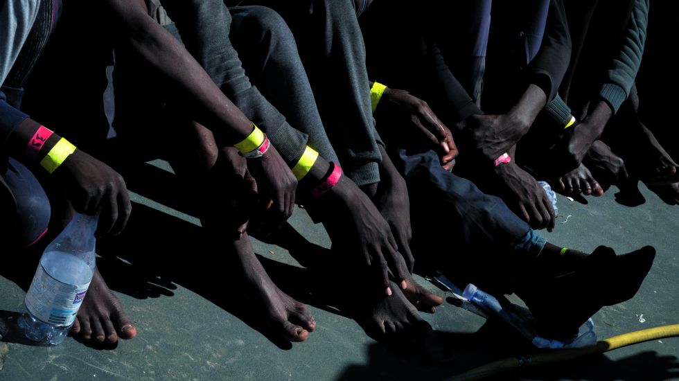 Füße und Hände von Flüchtlingen aus Afrika auf einem Boot der Küstenwache