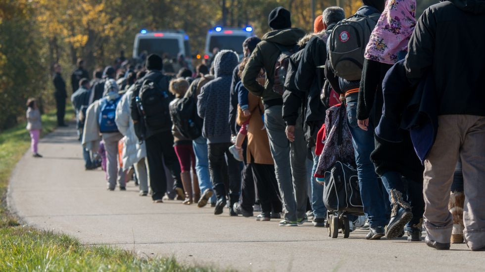Flüchtlinge gehen am 27.10.2015 nahe Wegscheid (Bayern) hinter Fahrzeugen der Bundespolizei