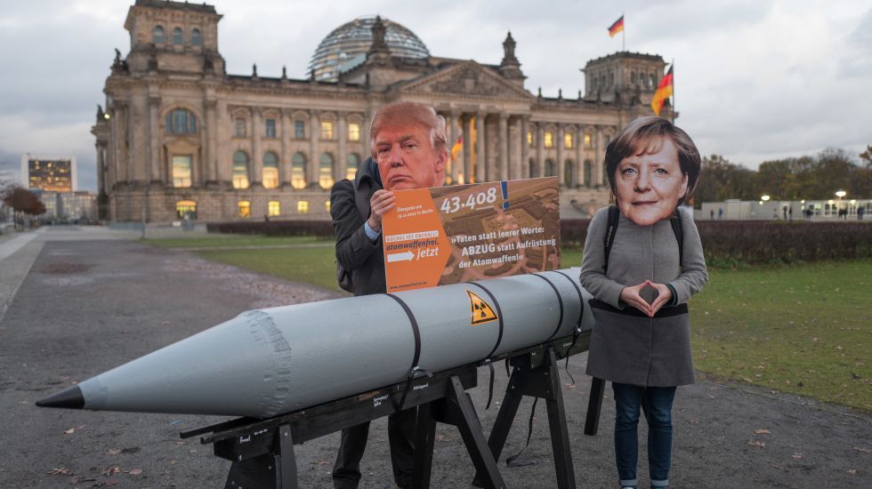 Mit Masken des US-Präsidenten und der Bundeskanzlerin und einer Atombomben-Attrappe stehen Aktivisten am 13.11.2017 vor dem Brandenburger Tor in Berlin und fordert den Stopp der nuklearen Aufrüstung und den Abzug der Atomwaffen aus Büchel (Rheinland-Pfalz). 