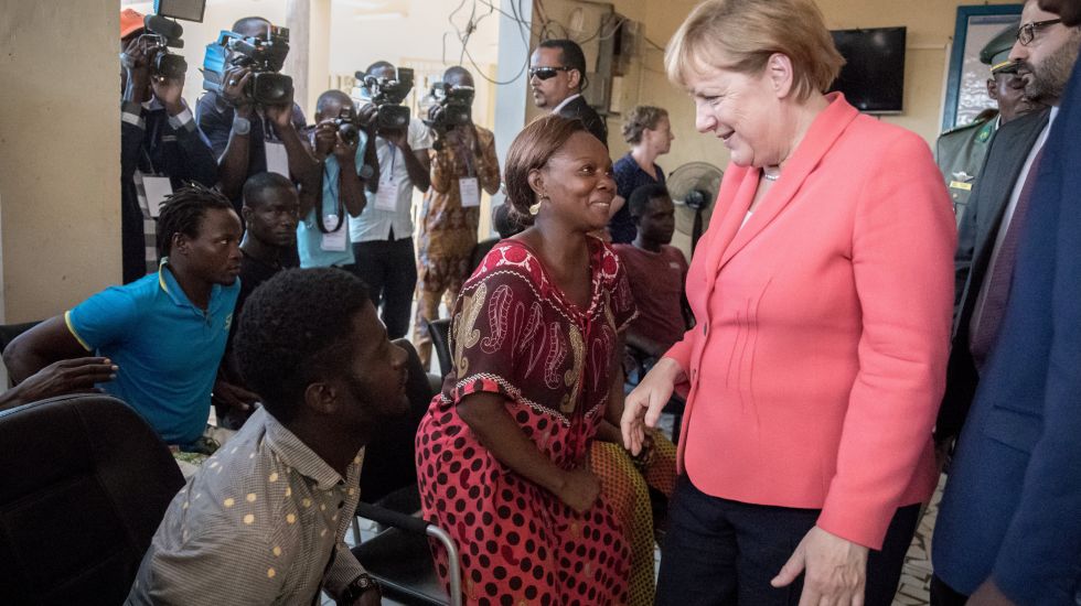 Bundeskanzlerin Angela Merkel (CDU) spricht am 10.10.2016 in Niamey im Niger im Aufnahme- und Durchangszentrum für Migranten der Internationalen Organisation für Migration mit Migranten (IOM) mit Flüchtlingen wie der Liberianerin Binta (M), die im Niger gestrandet sind. 