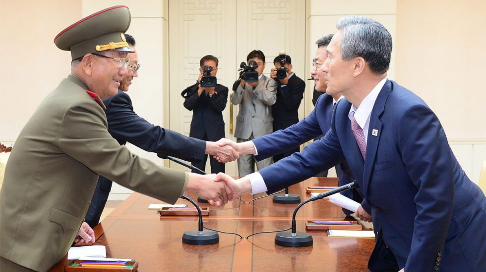 Vertreter Nord- und Südkoreas reichen sich über einem Tisch die Hand