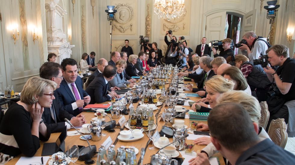 Die Mitglieder des neuen Bundeskabinetts sitzen im Schloss Meseberg an einem Tisch. 