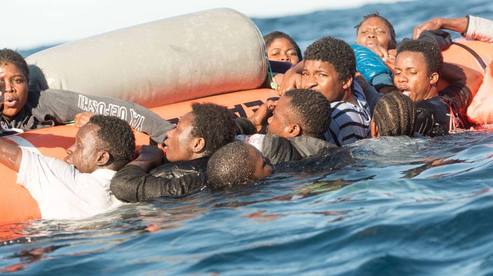 Zahlreiche Flüchtlinge, die auf Booten von Libyen aus nach Italien übersetzen wollten, klammern sich während eines Rettungseinsatzes am 27.01.2018 vor der libyschen Küste an einen Rettungsschlauch der Hilfsinitiative SOS Mediterranee.