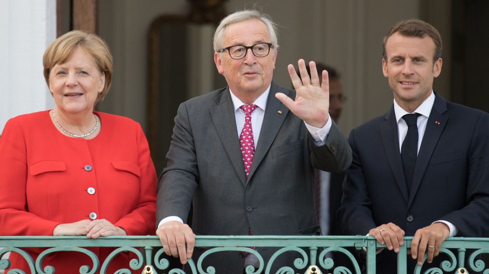 Emmanuel Macron (r), Präsident von Frankreich, Jean-Claude Juncker (M), Präsident der Europäischen Kommission, und Angela Merkel (CDU), Bundeskanzlerin, unterhalten sich zum Deutsch-Französischen Ministerrat vor Schloss Meseberg