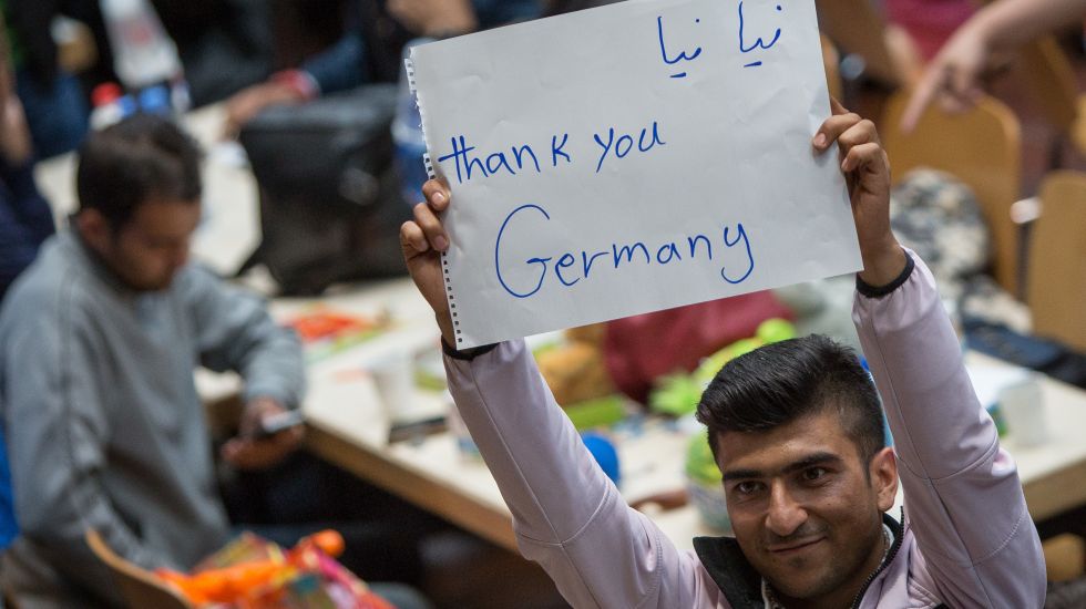 A refugge holds up a sign on which he wrote "Thank you Germany"