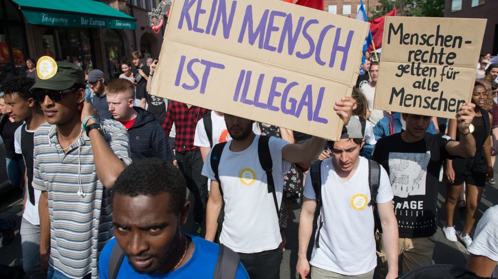 Teilnehmer einer Demonstration protestieren am 02.06.2017 in Nürnberg (Bayern) mit Schildern mit den Aufschriften "Menschenrechte gelten für alle Menschen" und "Kein Mensch ist illegal" gegen die bayerische Abschiebepraxis von Flüchtlingen.