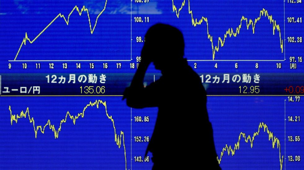 Ein Geschäftsmann geht vorbei am Nikkei-Index, der drastische Kurseinbrüche verzeichnet
