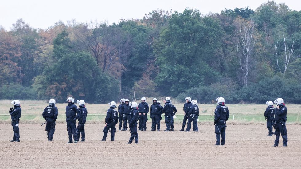 Polizisten stehen auf einem Feld vor dem Hambacher Forst