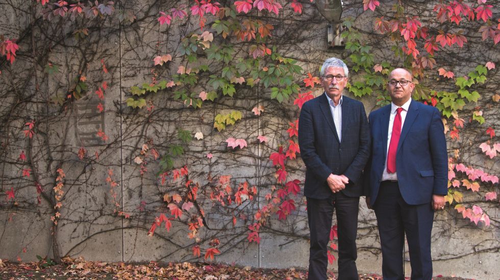Thilo Sarrazin und Abdel-Hakim Ourghi stehen vor einer Wand im Herbstlaub