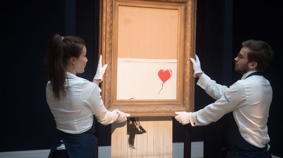 Zwei Mitarbeiter von Sotheby's halten das geschredderte Banksy-Bild