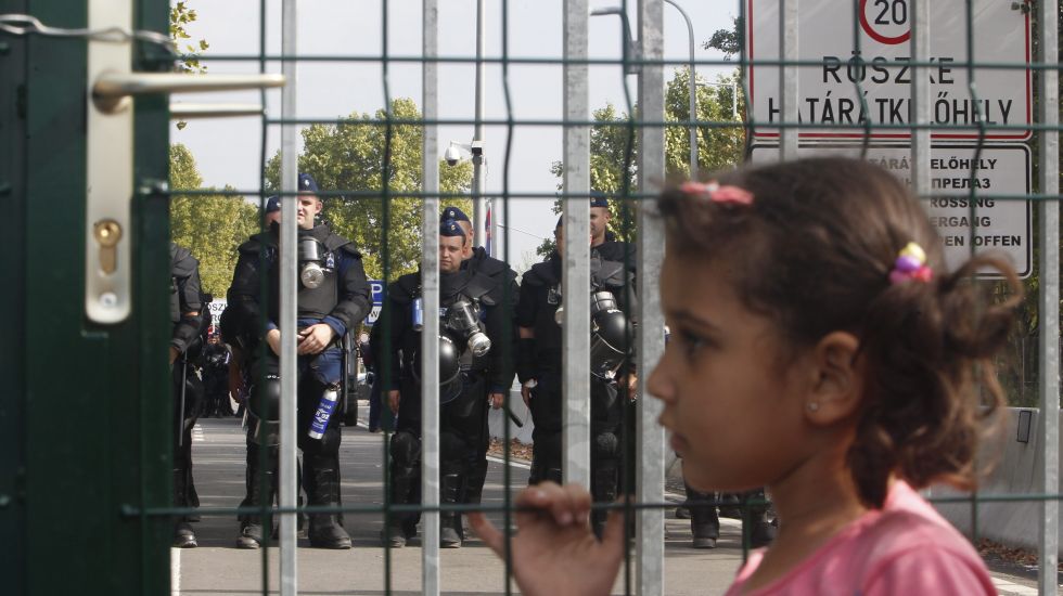 Ein kleines Mädchen steht am Grenzzaun der ungarischen Grenze zu Serbien