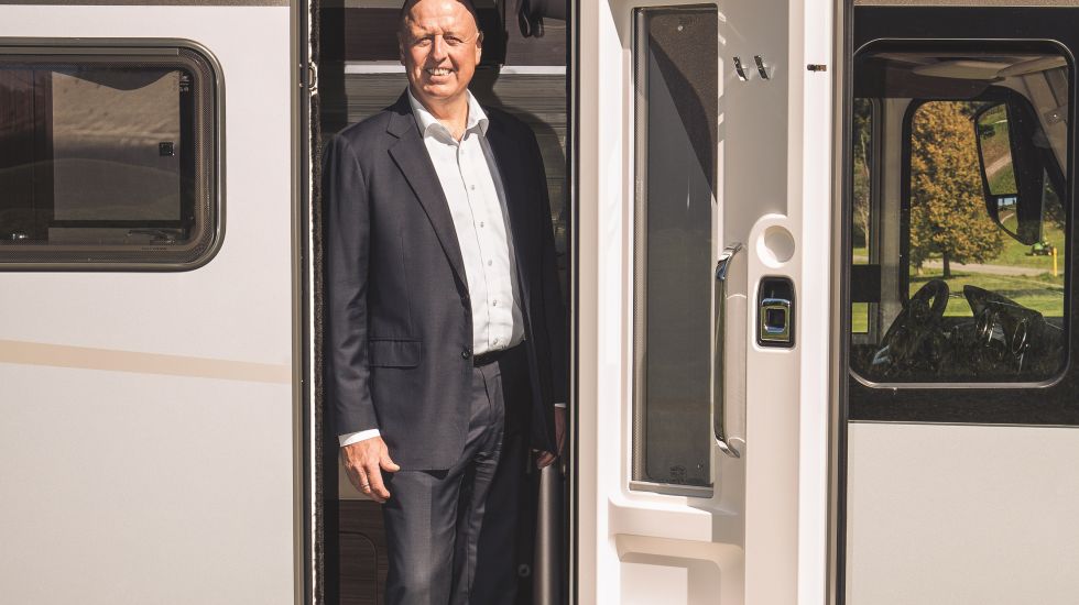 Martin Brandt steht in der Tür eines Wohnwagens und lächelt in die Kamera