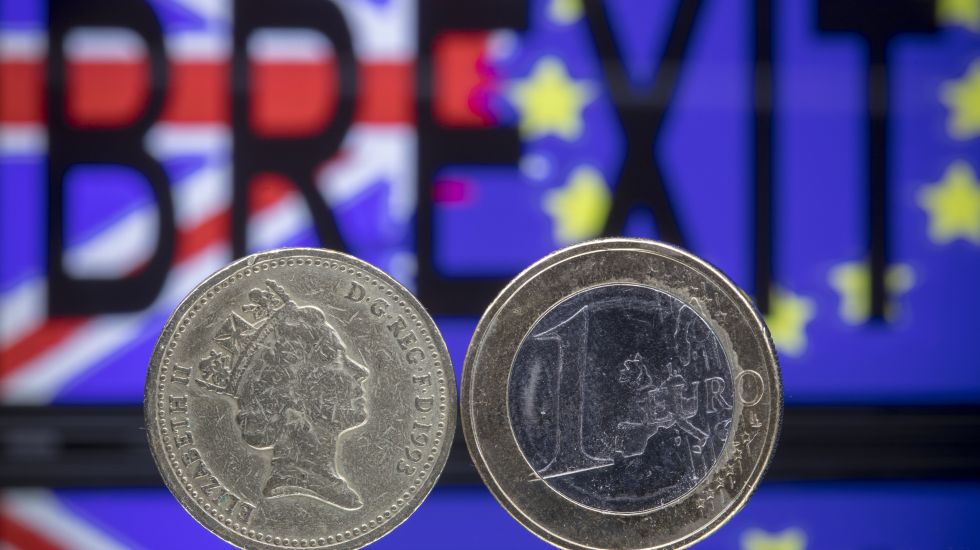 Eine Euro- und eine Pound-Münze stehen voreinander. Im Hintergrund steht Brexit geschrieben vor der europäischen und britischen Flagge.