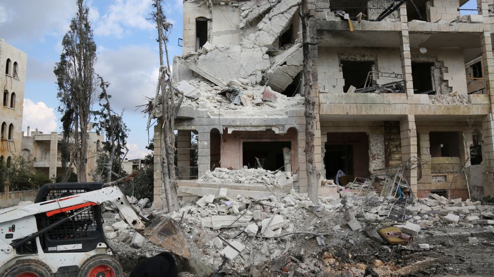 Ein zerstörtes Haus in Syrien. Davor steht ein Bagger.