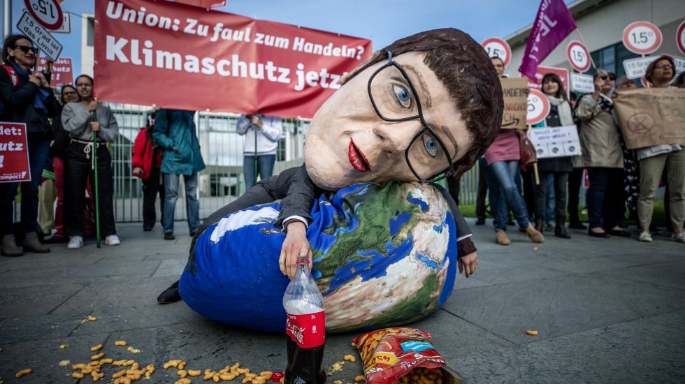 Eine Aktivistin von Campact liegt mit einer Großmaske, die die CDU-Vorsitzende Annegret Kramp-Karrenbauer darstellen soll, bei einer Kundgebung, die mangelnden Klimaschutz der Union bemängelt. Das Klimakabinett trifft sich gleichzeitig im Kanzleramt.