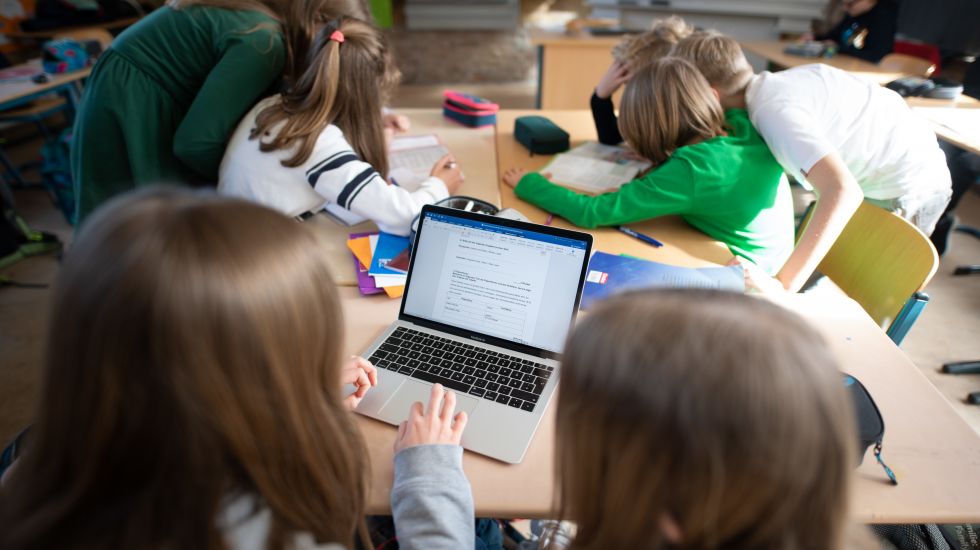 Schüler einer fünften Klasse eines Gymnasiums benutzen im Unterricht einen Laptop.