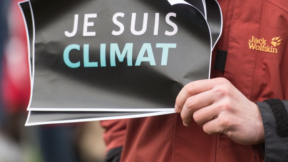 Ein Demonstrant hält ein Schild mit der Aufschrift "Je suis Climat".