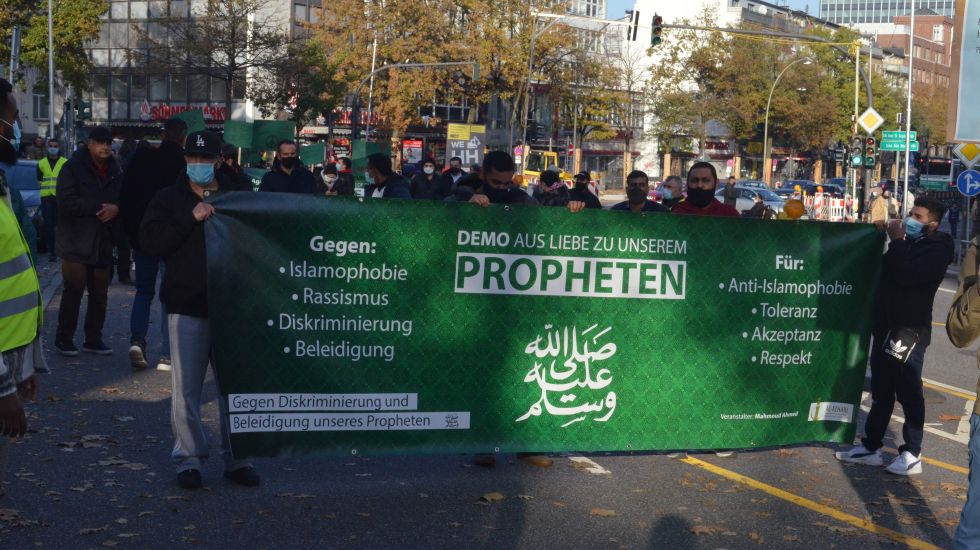 Demonstranten halten Plakat "Aus Liebe zu unserem Propheten" hoch