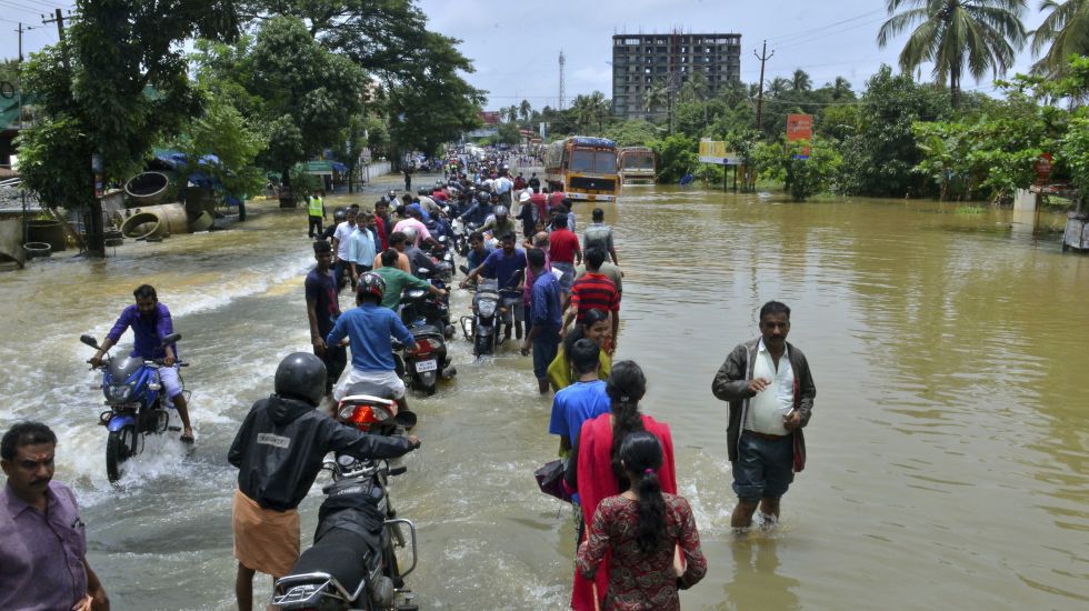  Menschen überqueren eine überflutete Straße im indischen Thrissur