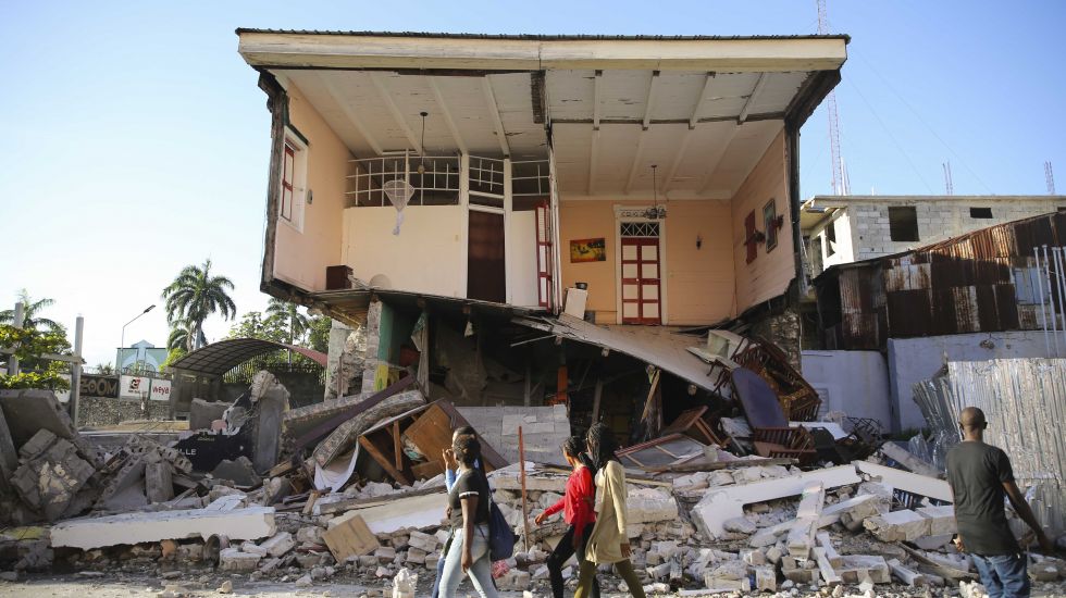 Haitianer vor zusammengestürztem Haus