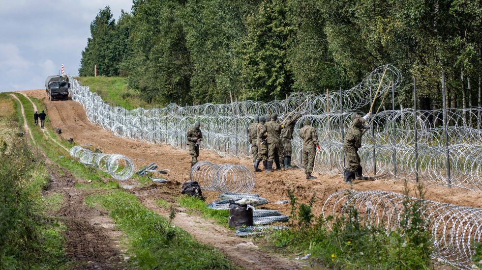 Polnische Soldaten errichten einen Stacheldrahtzaun