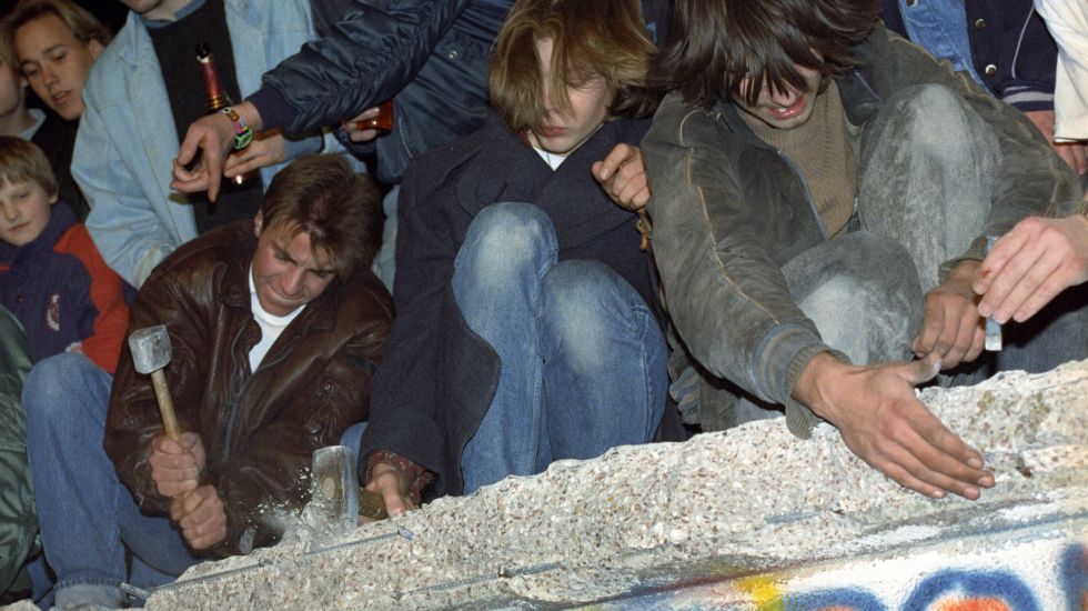 Das Archivbild vom 10.11.1989 zeigt West-Berliner, die mit Hämmern, Kreuzhacken und den bloßen Händen versuchen, die Berliner Mauer einzureißen.