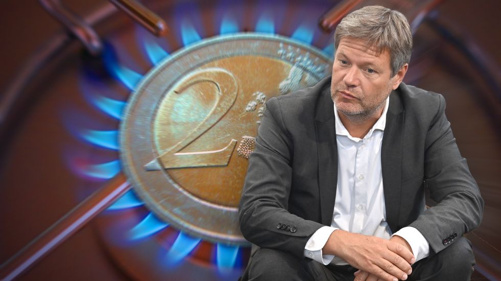 Robert Habeck sitzt vor dem Symbol einer 2 Euro Muenze, die auf einer Gasflamme zu liegen scheint