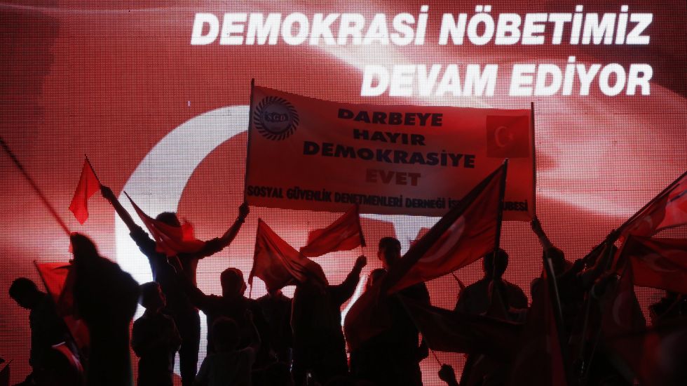 Erdogan-Unterstützer halten bei einer Kundgebung ein Transparent mit der Aufschrift „Nein zum Coup, Ja zur Demokratie“